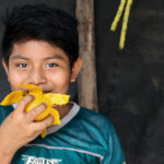 Niño, habitante de Yucatán, comiendo un mango.