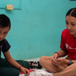 Miembro de nuestro staff ayudando a niñas y niños.