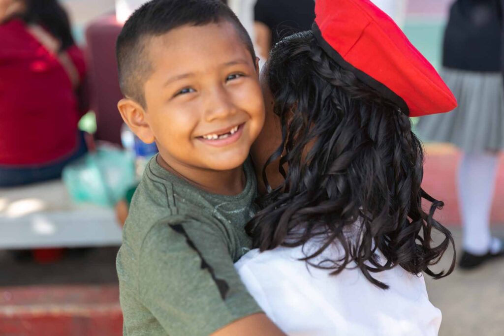 Niño sonriendo a la cámara en un abrazo.